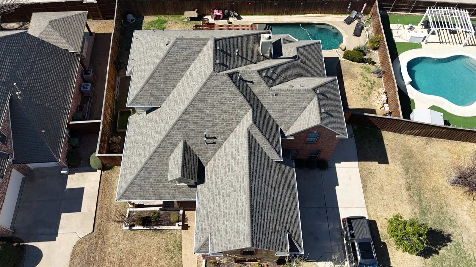 Top-down drone view of a new roof beside a pool